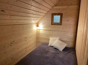 a small room with a bed in a log cabin at Camping nature 3 étoiles avec piscine - bord de rivière in Chézery-Forens