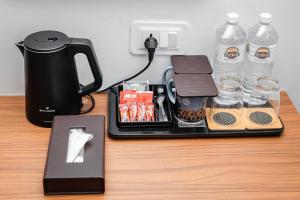 a tray with a coffee maker and bottles of water at GermanHomesHotel in Thimi