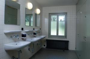 a bathroom with three sinks and two mirrors at Grindelwald Youth Hostel in Grindelwald +41 photos