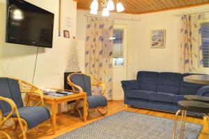 a living room with a couch and chairs and a tv at Alppitalo 2 as 1 in Tahkovuori