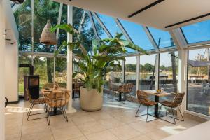 a conservatory with tables and chairs and a potted plant at LumiPod with Hot Tub | 2 Pers. in Wilsum