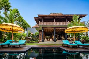a resort with a pool with blue chairs and umbrellas at The Joglo at Umah Sunset in Ubud