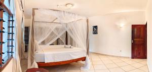 a bedroom with a bed with a canopy at Penety Villa in Shanzu +3 photos