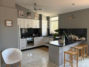 a kitchen with white cabinets and a black counter top at 10-Min Walk to Pearce Beach via Coastal Trail in Blairgowrie