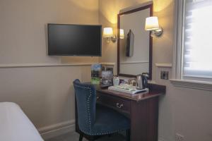 a hotel room with a desk with a mirror and a television at Birmingham North Moor Hall Hotel BW Premier Collection in Sutton Coldfield