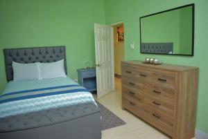a bedroom with a bed and a dresser with a mirror at Cedar Grove Luxe in Portmore