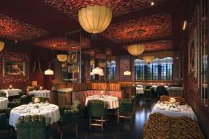 a dining room with tables and chairs and chandeliers at The Stoneleigh, Autograph Collection in Dallas