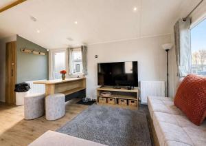 a living room with a couch and a flat screen tv at Kestrel Court 16 in Scratby