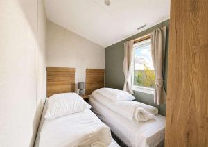 two beds in a small room with a window at Kestrel Court 16 in Scratby +10 photos