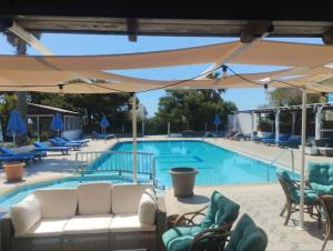 a swimming pool with chairs and an umbrella at Jack's Apartments in Kefalos