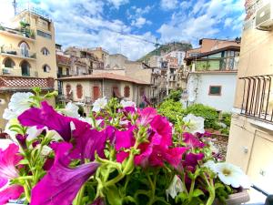 a bunch of flowers on a balcony with buildings at Tao House in Taormina