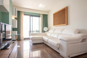 a living room with a white couch and a tv at Plaza España - Nerja centro in Nerja