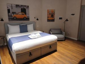 a bedroom with a large bed and a chair at Sette Vele Rooms in Trieste +57 photos