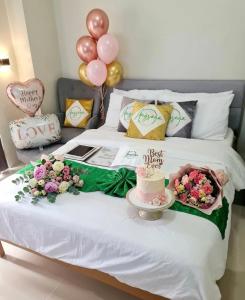a bed with a cake and balloons on it at Angsana Breeze-Alpine Crosswinds Tagaytay in Ulot