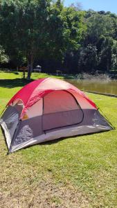 a tent sitting on the grass next to a lake at Camping Mairiporã in Mairiporã