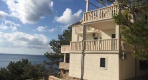 a white building with a balcony on top of it at Apartments Elvira in Sveta Nedelja