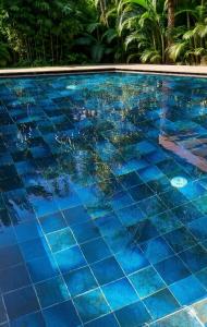 a swimming pool with blue tile floors and palm trees at Villa Majlis in Marrakesh