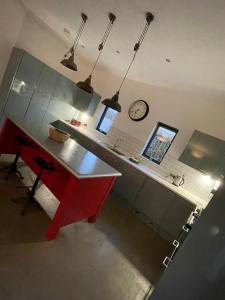a kitchen with a red desk and a clock on the wall at Umber, Gallery Cottages, Devon in West Putford