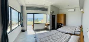 a bedroom with two beds and a view of the ocean at Khách Sạn View Biển - Homestay Sân Vườn - QUANG VINH Đảo Lý Sơn -Vị Trí Trung Tâm Đảo - Cạnh Bến cảng và Quảng trường in Ly Son