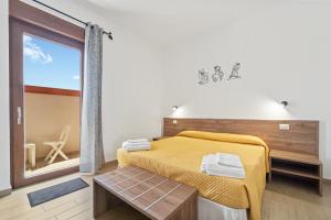 a bedroom with a yellow bed and a large window at CLASS ROOMS AFFITTACAMERE con bagno privato , vicino alle DUNE di PORTO PINO in SantʼAnna Arresi