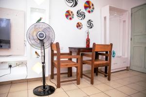 a room with a table and a fan and chairs at Angie's Cozy Studio Diani Beach in Ukunda +5 photos