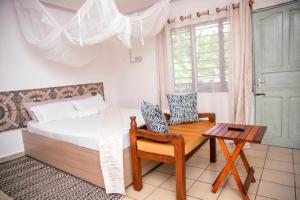 a bedroom with a bed and a table and a chair at Angie's Cozy Studio Diani Beach in Ukunda