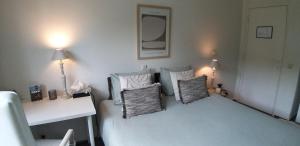 a bedroom with a white bed with pillows and a mirror at logies Huis Liselotte in Genk