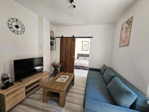 a living room with a blue couch and a tv at Apartman ANTEO in Slavonski Brod