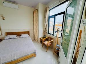 a bedroom with a bed and a large window at Khách Sạn View Biển - Homestay Sân Vườn - QUANG VINH Đảo Lý Sơn -Vị Trí Trung Tâm Đảo - Cạnh Bến cảng và Quảng trường in Ly Son