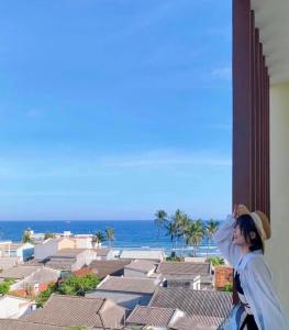 a woman standing on a building looking at the ocean at Khách Sạn View Biển - Homestay Sân Vườn - QUANG VINH Đảo Lý Sơn -Vị Trí Trung Tâm Đảo - Cạnh Bến cảng và Quảng trường in Ly Son