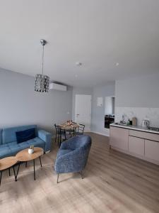 a living room with a blue couch and a kitchen at Apartments ABC in Mostar
