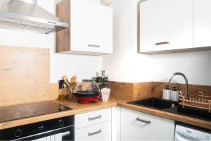 a kitchen with white cabinets and a sink at Évasion étoilée in Corbeil-Essonnes