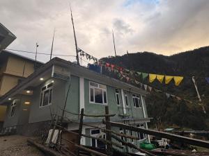 a house with prayer flags on the side of it at Mayal Lyang Lachung in Mangan
