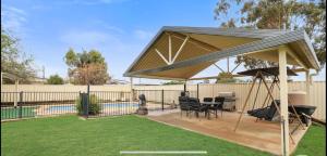 a pavilion with a table and chairs and a pool at Taking 5 in West Tamworth