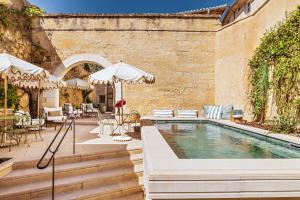 an outdoor pool with tables and chairs and an umbrella at La Maison d'Uzès Relais & Châteaux in Uzès