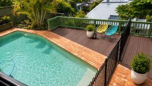 a swimming pool with two chairs and a table on a deck at Sunlit Lodge in Rochedale South