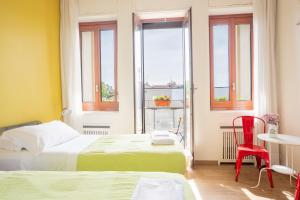 a hotel room with two beds and a table and chairs at Ostello Bello Milano Centrale in Milan