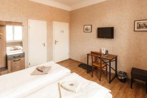 a bedroom with two beds and a table and a television at Hotel Ratsstuben Kalbe in Kalbe