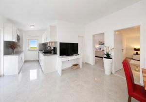 a white kitchen with a flat screen tv on a wall at Apartments ROSINI, 300m from the beach with shared tavern and bikes, Nin in Nin