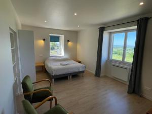 a bedroom with a bed and two windows and a chair at La ferme Bourguignonne in Saizy