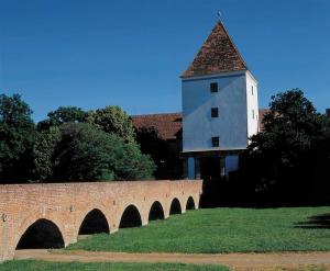 a building with a tower on top of a brick bridge at Rubin Verde Residence in Sárvár