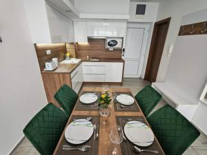 a kitchen with a dining table with green chairs at Rubin Verde Residence in Sárvár