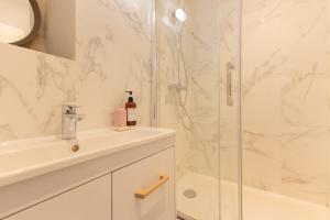 a white bathroom with a shower and a sink at Magnifiques Appartements - Face a la Gare in Bordeaux