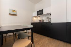 a kitchen with black cabinets and a table and chairs at Magnifiques Appartements - Face a la Gare in Bordeaux