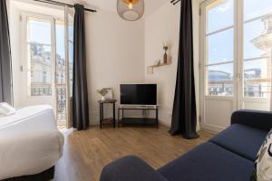 a living room with a bed and a tv at Magnifiques Appartements - Face a la Gare in Bordeaux +56 photos
