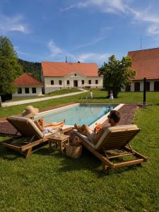two people laying in lawn chairs next to a swimming pool at Rezidenca Korman in Fala