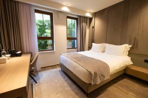 a bedroom with a bed and a desk and windows at Sapphire Hotel in Prizren +53 photos