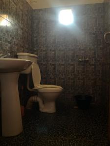 a bathroom with a toilet and a sink and a light at Sumanya guest house 3 in Sukuta
