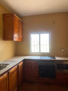 a kitchen with wooden cabinets and a sink and a window at Sumanya guest house 3 in Sukuta +18 photos