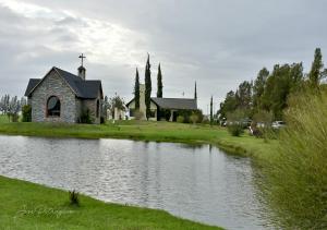 a church next to a river with a church at Hotel Raices del Arapey in Termas del Arapey